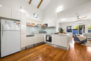 an open kitchen and living room with white cabinets at Rocky Shores Hideaway in South West Rocks +13 photos