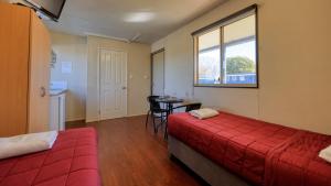 a room with two beds and a table and a window at River Gum Tourist Park in Saint George