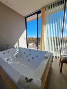 a large white bath tub in a room with a large window at ENTREVID suites & spa in Anchoris