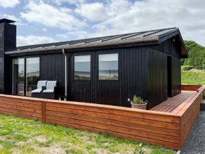 a black house with a wooden deck at 6 person holiday home in Sjølund-By Traum in Binderup Strand +32 photos