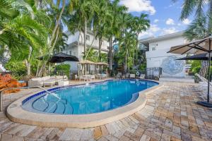 a swimming pool with palm trees in front of a building at Isle of Venice Residence and Marina in Fort Lauderdale