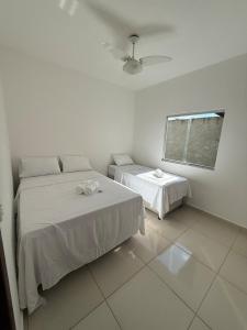 a white room with two beds and a window at Casa aconchegante e cheirosa in Nanuque
