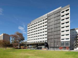 a large office building with a grass field in front of it at Mantra MacArthur Hotel in Canberra