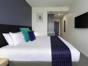 a bedroom with a large white bed with pillows at Mantra MacArthur Hotel in Canberra