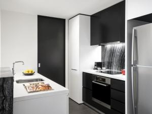 une cuisine avec des comptoirs blancs et des armoires noires dans l'établissement Peppers Gallery Hotel, à Canberra