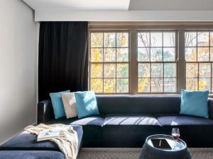a living room with a blue couch and windows at Peppers Gallery Hotel in Canberra