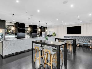 a bar with black tables and chairs and a tv at Mantra on Russell in Melbourne