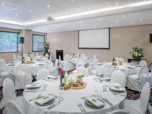 a conference room with white tables and chairs and a screen at Mantra on Russell in Melbourne +53 photos