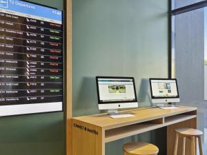 two computer monitors sitting on a desk with a screen at Mantra on Sydney Airport in Sydney