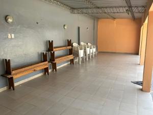 une salle d'attente avec des bancs en bois et des chaises blanches dans l'établissement Casa de descanso Emiliano, à Salta 1 autre photo