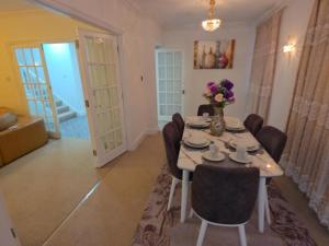a dining room with a table with chairs and flowers on it at First Class Luxurious Apartment London Finchley in Brent Station +28 photos