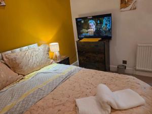 a bedroom with a bed with a television on a dresser at First Class Luxurious Apartment London Finchley in Brent Station