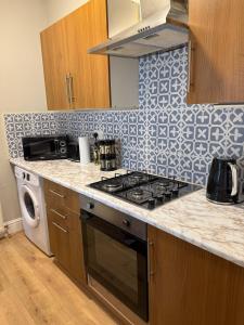 una cocina con estufa horno superior al lado de un lavavajillas en Cosy Jesmond Retreat!, en Jesmond