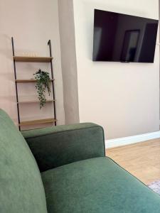 Una sala de estar con un sofá verde y un televisor. en Cosy Jesmond Retreat!, en Jesmond 12 fotos más
