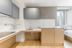 eine Küche mit weißen Arbeitsflächen, einem Waschbecken und einem Bett in der Unterkunft Accessible Studio In Central Leeds in Central Station