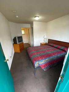 a small bedroom with a bed and a tv at Tacoma Center Motel in Tacoma