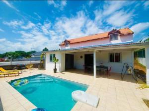 una villa con piscina frente a una casa en Villa La Cruzanelle, en Sainte-Rose