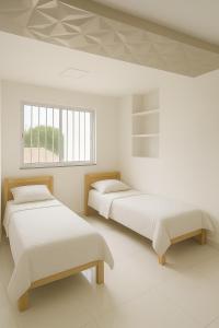 two beds in a white room with a window at Casa para cop 30 in Belém