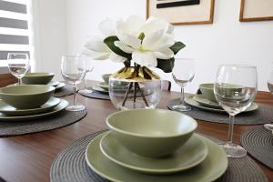 a table with plates and glasses and a flower in a vase at Chappelle with AC King Beds Fenced Yard Garage in Edmonton +71 photos