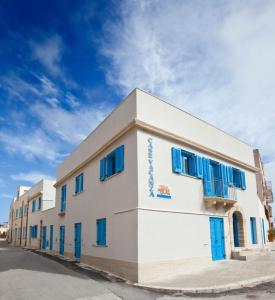 a white building with blue shutters on it at Terra del Sole in Favignana