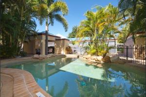 a swimming pool with palm trees in a yard at 4/100 The Esplanade in Belgian Gardens
