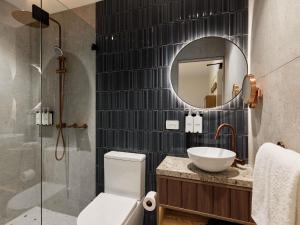 ein Badezimmer mit Toilette, Waschbecken und Spiegel in der Unterkunft The Clarence Hotel Sydney in Sydney