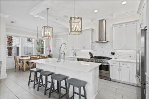 a kitchen with white cabinets and a kitchen island with bar stools at Mermaid Cove in Inlet Beach