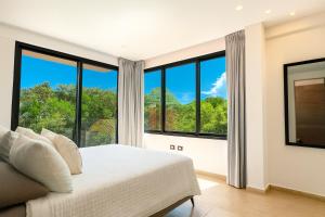 a bedroom with a bed and large windows at Puerto Aventuras Private Terrace and Golf View in Puerto Aventuras