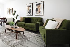 a living room with two green couches and a coffee table at Chappelle with AC King Beds Fenced Yard Garage in Edmonton