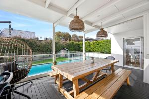 an outdoor patio with a wooden table and chairs at Beach Road Pool Escape in Torquay