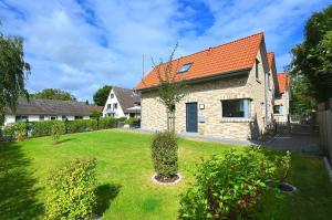 ホーヴァハトにあるDie-Strandburg-Moewenwegの庭にオレンジの屋根を持つレンガ造りの家