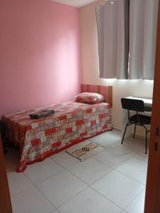 een kleine slaapkamer met een bed en een bureau bij Doce lar in Montes Claros