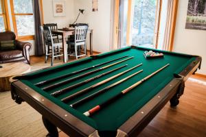 a pool table with cuesticks in a living room at Sierra Mountain Escape - Brand new spa/game room! in Yosemite Forks