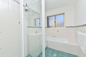 Un baño blanco con bañera y lavabo. en Salt and Paws at Fingal Bay, en Fingal Bay 18 fotos más