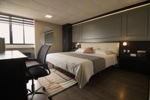 昆卡Hotel Italia Cuenca - Tranvia Centro & Aeropuerto的一间卧室,配有一张床、一张桌子和一把椅子