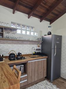 a kitchen with a stainless steel refrigerator and wooden cabinets at Cabana Sol Poente PR in São José dos Pinhais