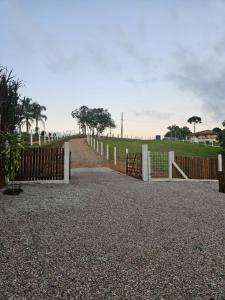 a wooden fence with a gate in a field at Cabana Sol Poente PR in São José dos Pinhais +5 photos