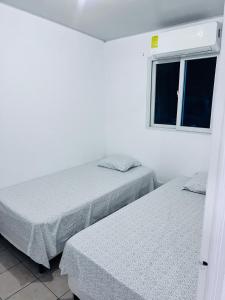 Dos camas en una habitación blanca con ventana. en Lugar tranquilo, en Sitio Grande 26 fotos más