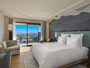 une chambre avec un grand lit blanc et une chaise dans l'établissement Swissotel Resort And Spa Cesme, à Çeşme