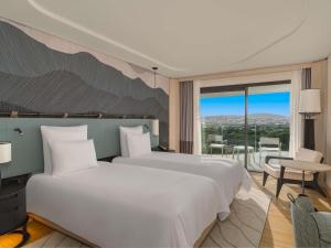 une chambre avec un grand lit blanc et un balcon dans l'établissement Swissotel Resort And Spa Cesme, à Çeşme