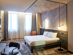 a hotel room with a bed and a table and chairs at Novotel Rouen Centre Cathédrale in Rouen