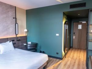 a bedroom with a white bed and a blue wall at Novotel Rouen Centre Cathédrale in Rouen