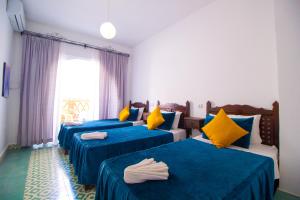 a room with three beds with blue and yellow pillows at Maison d'hôte Bousaid in Chefchaouene +47 photos
