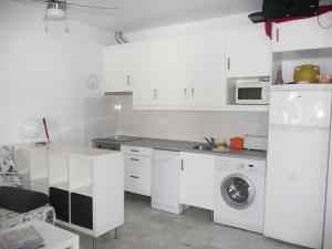 a kitchen with white cabinets and a washing machine at Paraíso Veracoast in Vera