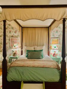 a bedroom with a canopy bed with floral wallpaper at 3BR 2BA Historic Mid City family BACH parties FQ!! in New Orleans