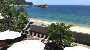 a view of a beach with some umbrellas and the ocean at Yuinoya MITSUBACHI in Imabari