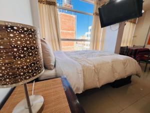 Un dormitorio con una cama y una ventana grande en MiniDepartamento Plaza de Armas, en Puno