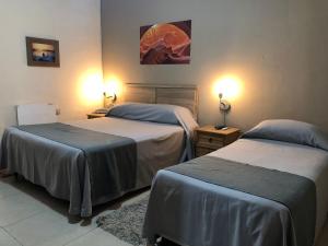 two beds in a hotel room with two lamps at Hotel Durazno in Durazno