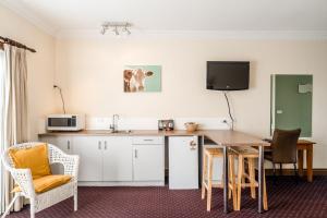 a room with a kitchen with a table and a desk at The Henry Parkes Tenterfield in Tenterfield