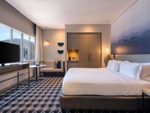 a hotel room with a large bed and a television at Pullman Cape Town City Centre in Cape Town